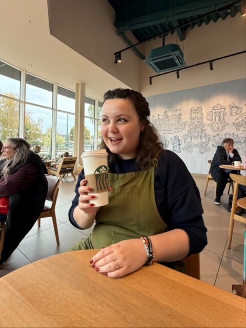 The compulsory pumpkin spice latte photo - a bit late this year, but I assure you, many were consumed during the season 😂VD: A white woman with brown hair, wearing a green dungerees set. She is sitting in a Starbucks with a coffee cup. 🍂