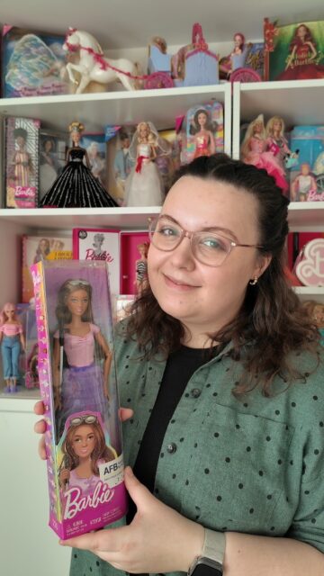 Happy World Braille Day 2026!Braille is a code that uses bumps and indentation on a surface to represent letters, which can be recognised by touch. Louis Braille, a French man who was blinded in an accident at a very young age, invented it.Before Braille invented this form of communication, many visually impaired people read and wrote using other systems which embossed letters on thick paper or leather. This was complicated as you can imagine and only allowed people to read, not write. Discouraged by this, Louis Braille invented the Braille code in his teen years. It's now estimated that about 250,000 people in the UK use it to read and write. It's important to note that not all visually impaired people use braille, but many do.Mattel have released the first Barbie doll with visual impairment as part of their fashionistas range. The collection includes dolls with lots of different disabilities to create a more inclusive Barbie world. She's a brilliant addition to my collection, which disability do you think that Mattel should do next?VD: A white haired woman, with brown hair, wearing a teal shirt, stood in front of shelves of Barbie dolls throughout the years.