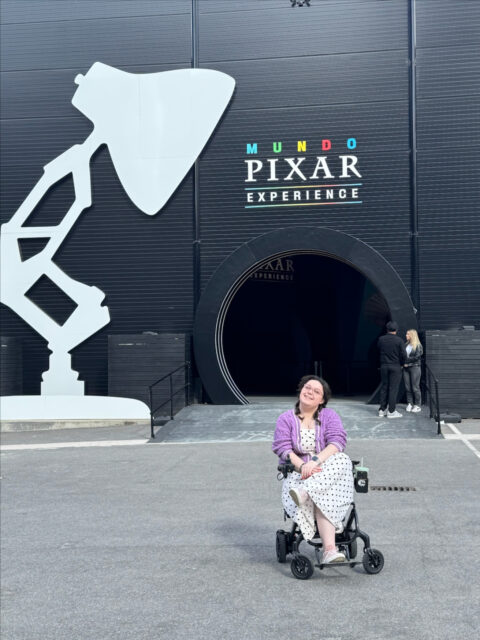 I went to Disney (Well, the Disney Mundo Exhibit)!A magical couple of hours spent adventuring around some of the most-loved Pixar sets, pretending I was a toy in my favourite parts of all the films. I have an album jam packed full of photos and plenty more to share.For anyone wondering, accessibility was really good throughout (with disabled toilets near the main entrance), but it is crowded so I'd recommend not being in a hurry. I found it best to remain near the rear of the group so that I had room to see each set.VD:
Image 1)  A white woman, with brown hair in bubble braids sitting crossed legged in her wheelchair, smiling. She is wearing a white dress, with a black spots and a lilac cardigan. She is sitting in front of the entrance to the Mundo Pixar Experience with the Pixar lamp to the left of her.Image 2) Imali, a white woman with brown hair in bubble braids, sitting in a wheelchair. She is wearing a lilac colour cardigan with a white and black polka dot dress. Above her is a Disney + logo, with the tagline 'A lifetime of great stories'. She has her hands in the air.Image 3) Imali (still wearing the same outfit!) wearing purple Mickey ears, sitting in one of the sets in the exhibit with Woody from Toy Story.