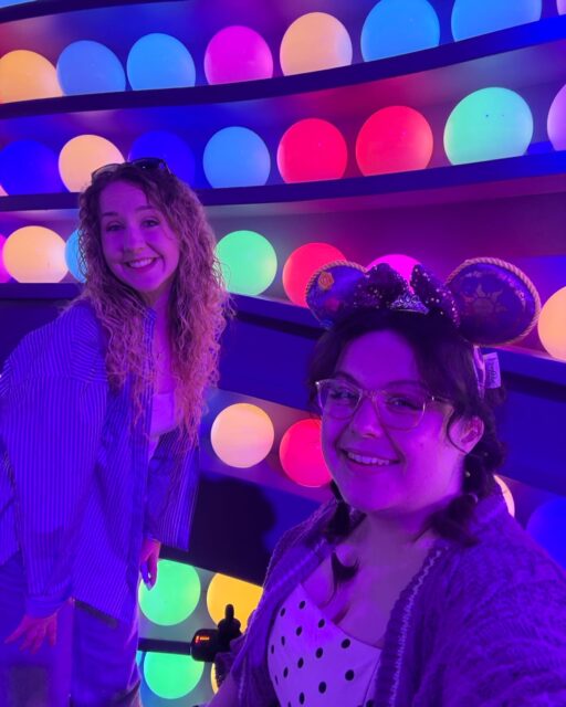 Happy Disney daysVD: Two white woman in a UV lit room with ‘core memory’ balls in the background from Inside Out. Both women are smiling.