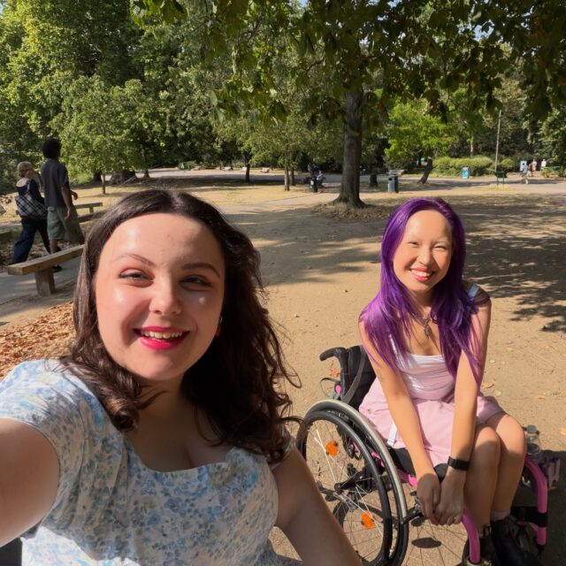 I can now officially add ‘Model’ to my CV 👀 What an experience! Met the lovely @presentedbyjo along with so many others. Can’t share any photos yet, but keep your eyes out for me - I’m often told I pop up in unexpected places!VD: A white woman, with brown curled hair, looking rather warm in a blue dress. She is taking a selfie in a bright, sunny park. Next to her is an incredible human with purple hair and a pink dress. Both are wheelchair users.