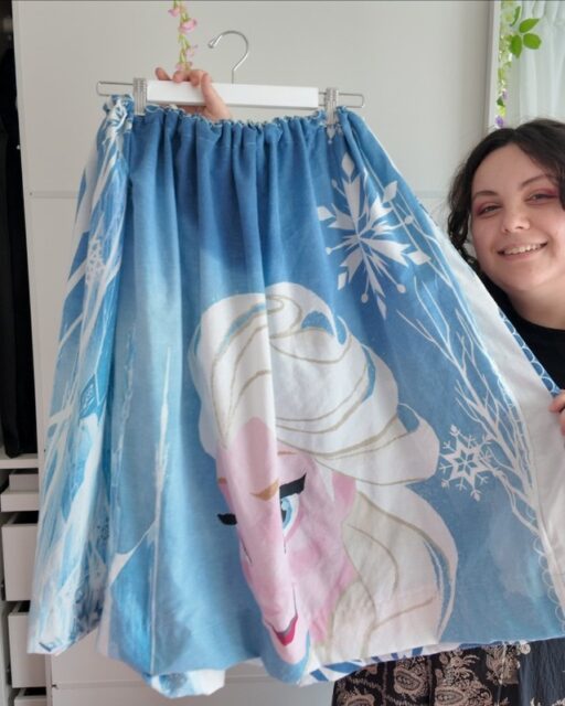 Swipe to see some of my Disneybound outfit finds - each of these is secondhand and the skirt I made myself from a childs bedsheet - all three cost me less than £20!  Showing you that you can capture the Disney aesthetic on a budget.VD: A white woman, with brown hair wearing a black top. In each photo she is holding a garment. The first is a blue Frozen skirt, with Elsa on it. The second is a purple dress with abstract flowers and the third is a red gingham top.
