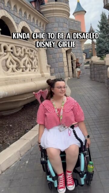 Just a girl with Mickey ears and a dream ✨VD: A white woman, with brown hair, wearing a red gingham top and white shorts, in a blue wheelchair. She is wheeling past the castle at Disneyland Paris(Hashtags)
#DisneylandParis @DisabledAtDisney