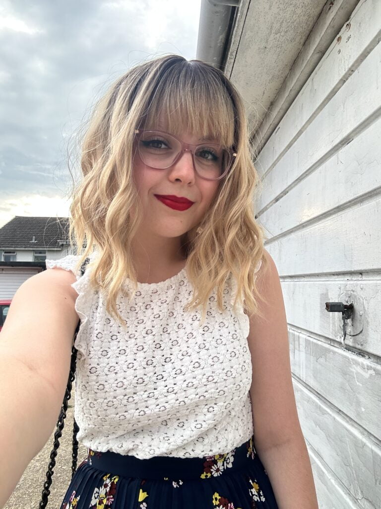 Woman with blond hair taking a selfie, wearing a white blouse
